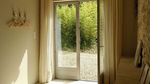 A room with a sliding glass door leading to an outdoor area with gravel and greenery. - Les Foucauds. A little paradise among the vines (Saint-Quentin-de-Caplong)