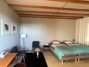 Une chambre d’hôtel comprenant un lit, un bureau, une chaise, une petite table et une lampe.