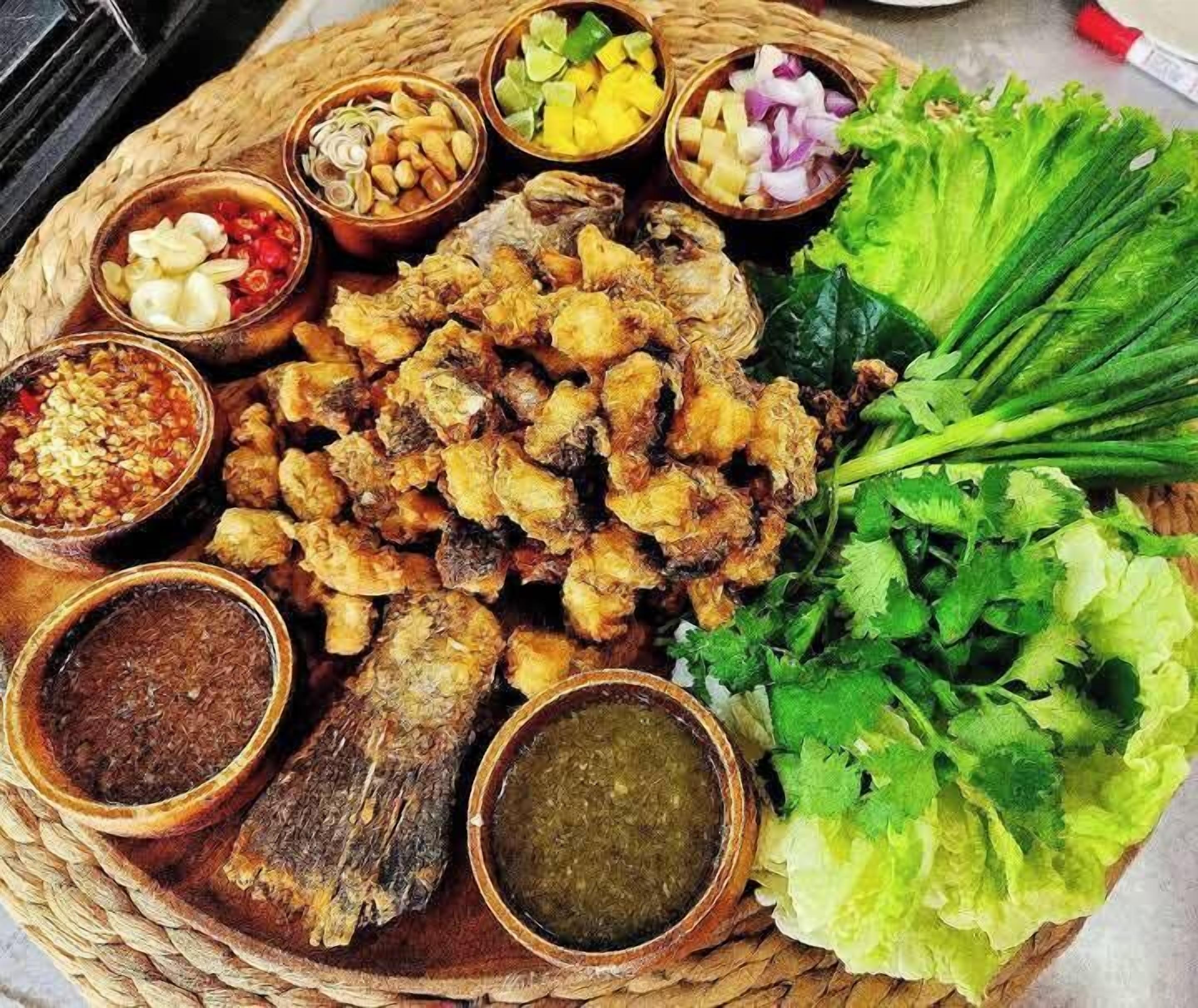 Variedad de alimentos fritos y verduras frescas sobre una bandeja trenzada.