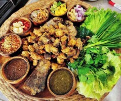 Variedad de alimentos fritos y verduras frescas sobre una bandeja trenzada.