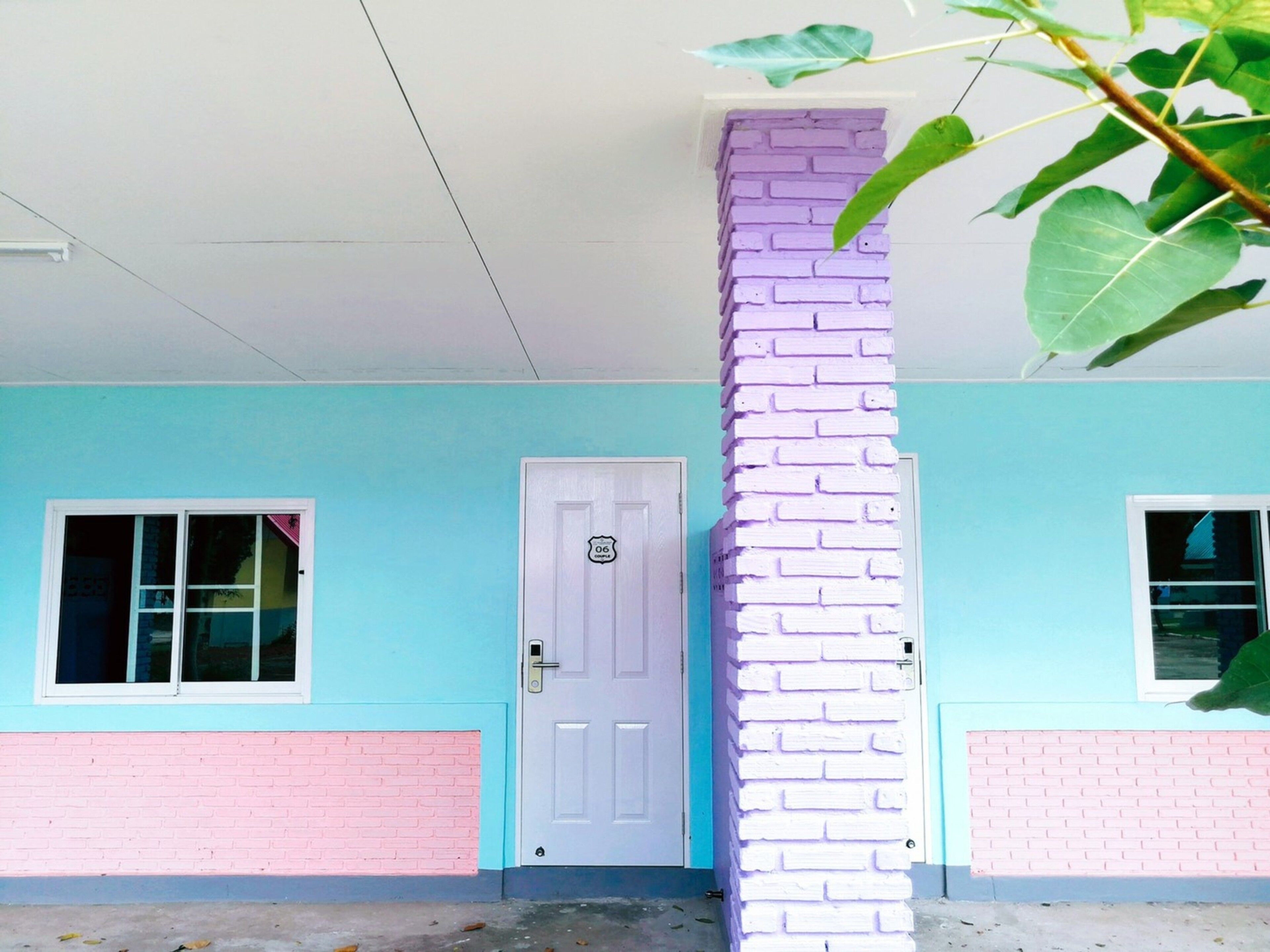 A building with a light blue exterior, a white door, and a pink brick base.