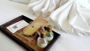 A neatly made bed with white towels arranged in the shape of two swans, a tray with toiletries, and a pillow. - Muang Loei Airport Hotel (Mueang Loei)