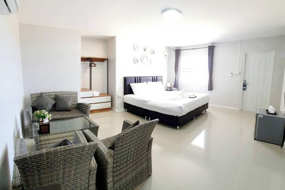 Una habitación de hotel moderna con una cama grande, un sofá, una mesita y una silla.
