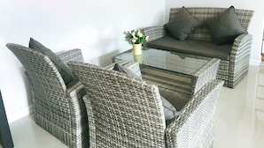 A wicker sofa and chairs with a glass coffee table, a small potted plant, and a grey cushion. - Muang Loei Airport Hotel (Mueang Loei)