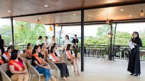 A covered outdoor seating area with wicker chairs and a speaker addressing the audience. - Muang Loei Airport Hotel (Mueang Loei)