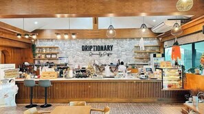A coffee shop interior with a wooden counter, stone wall, and hanging pendant lights. - Muang Loei Airport Hotel (Mueang Loei)