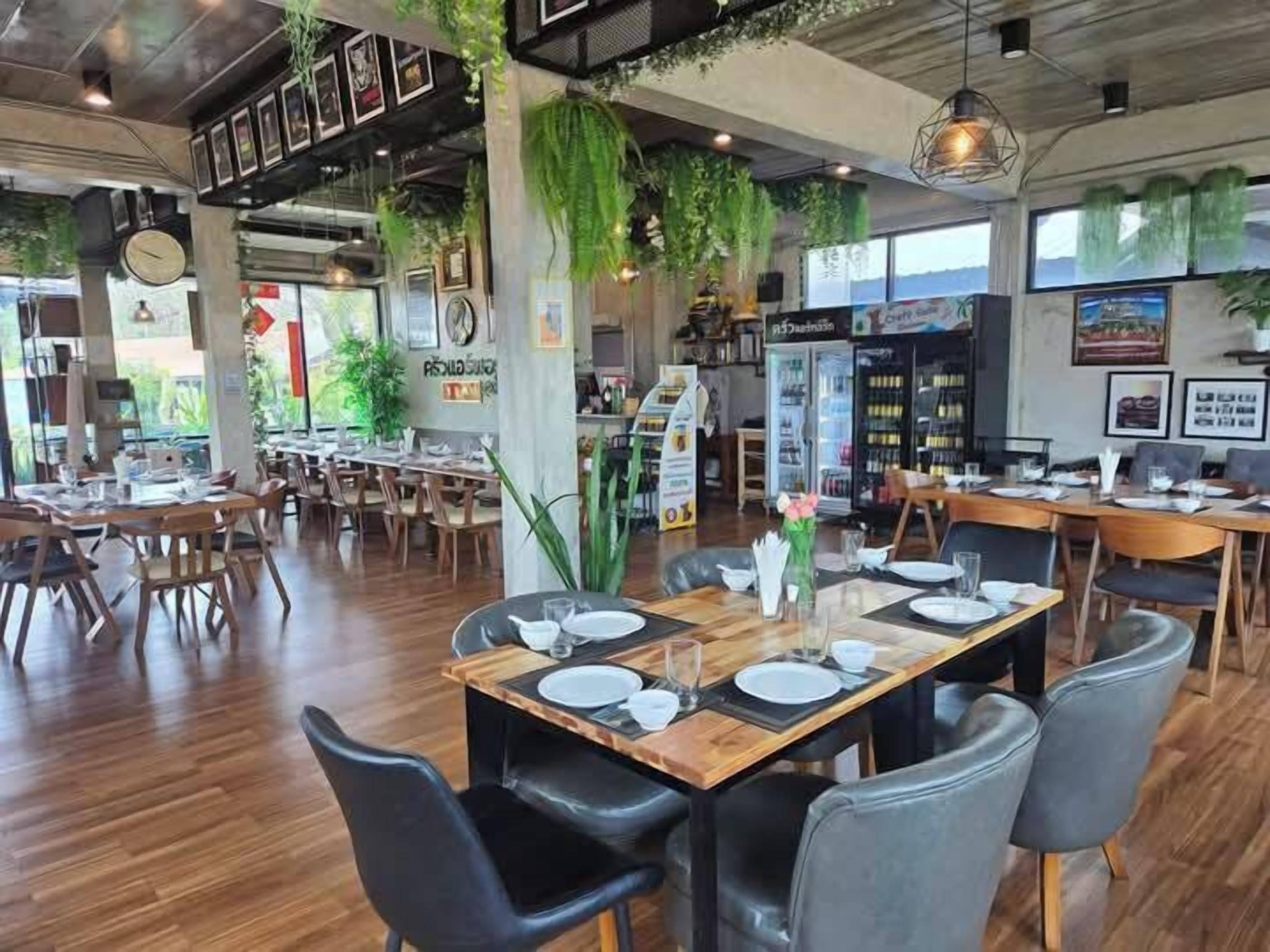 Ein Restaurant mit Holztischen und -stühlen, Zimmerpflanzen und einem modernen Interieur.