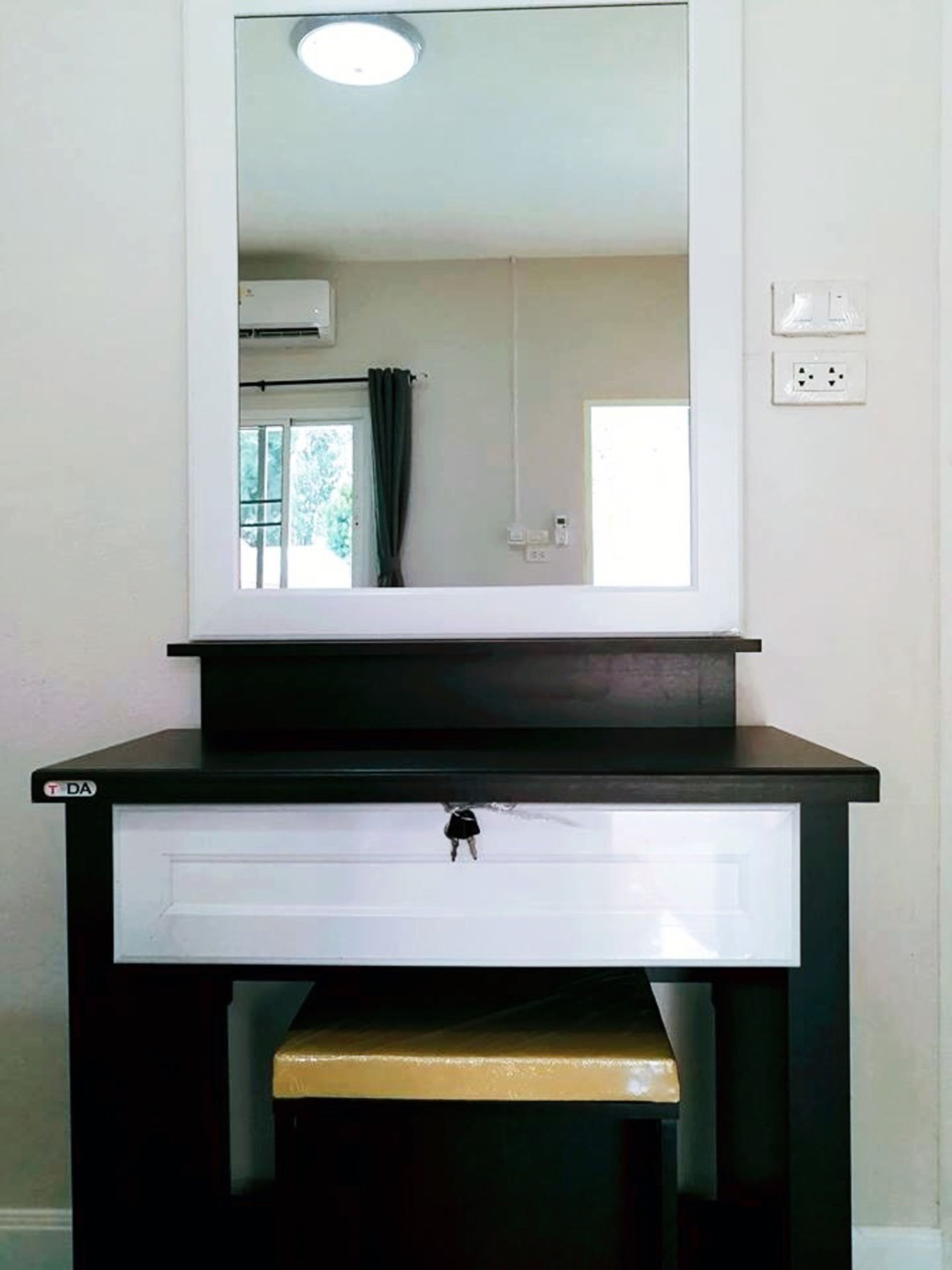 Een badkamer met een zwarte wastafel, een witte lade en een spiegel erboven.