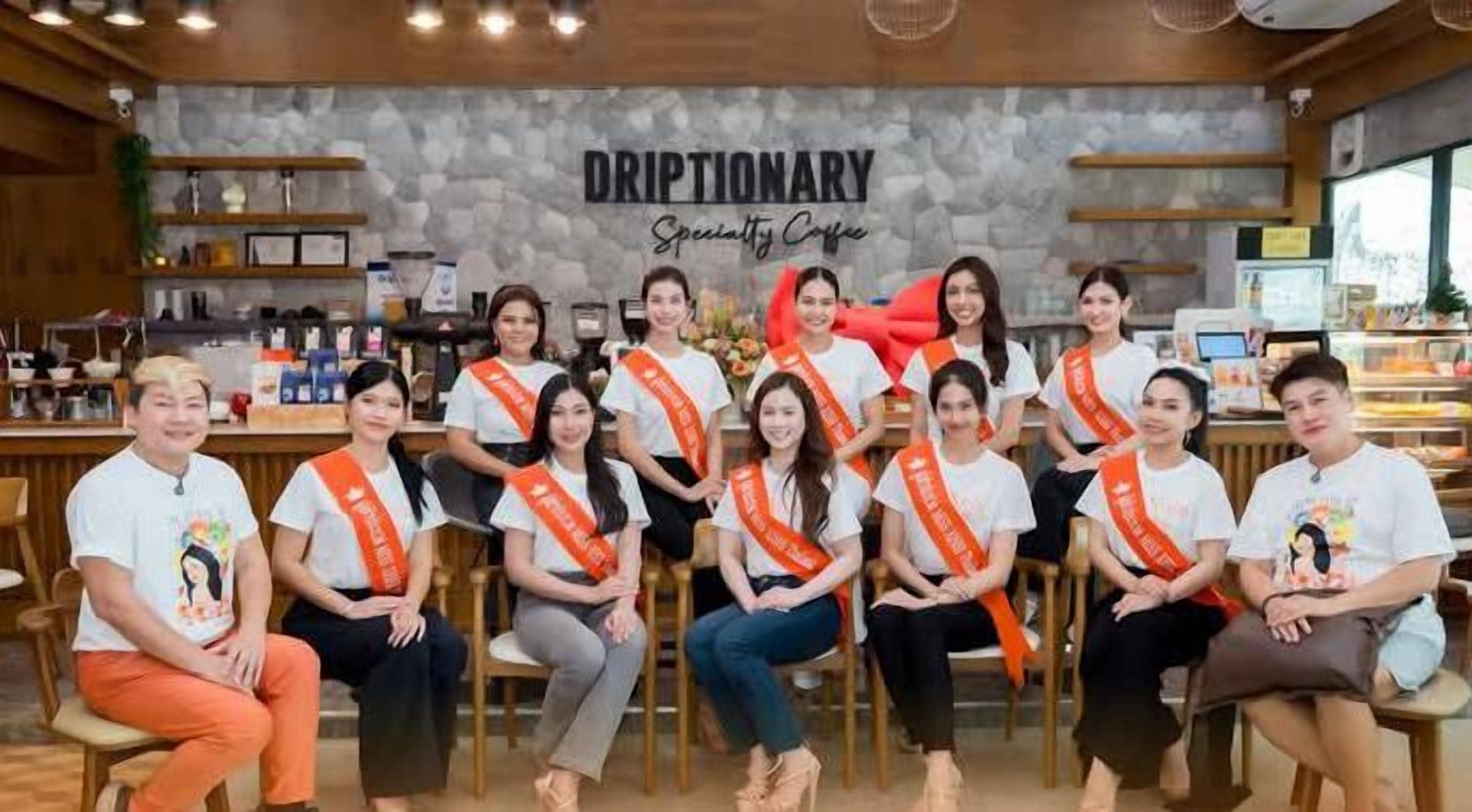 Un grupo de personas sentadas en un café, con un letrero que dice “DRIPTIONARY Specialty Coffee” al fondo.