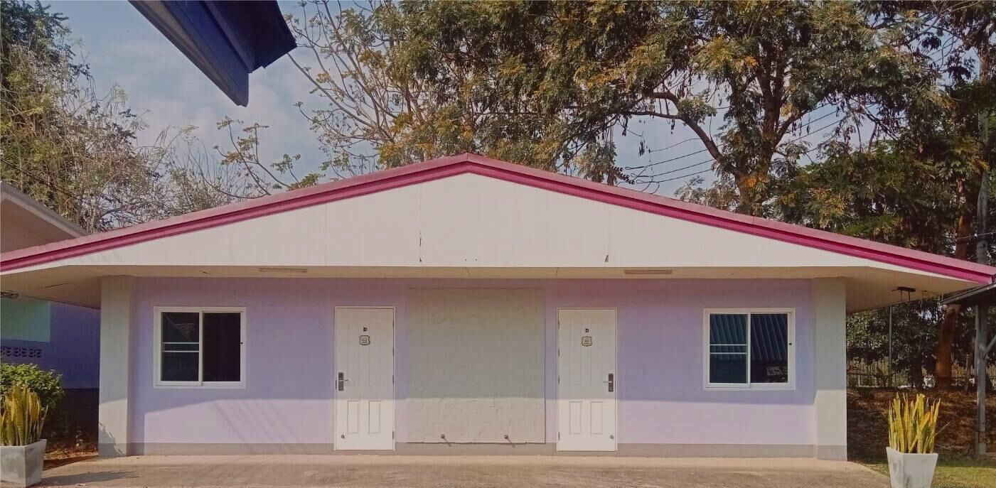 A single-story building with a flat roof and a red trim. It has two doors and two windows on the front facade.