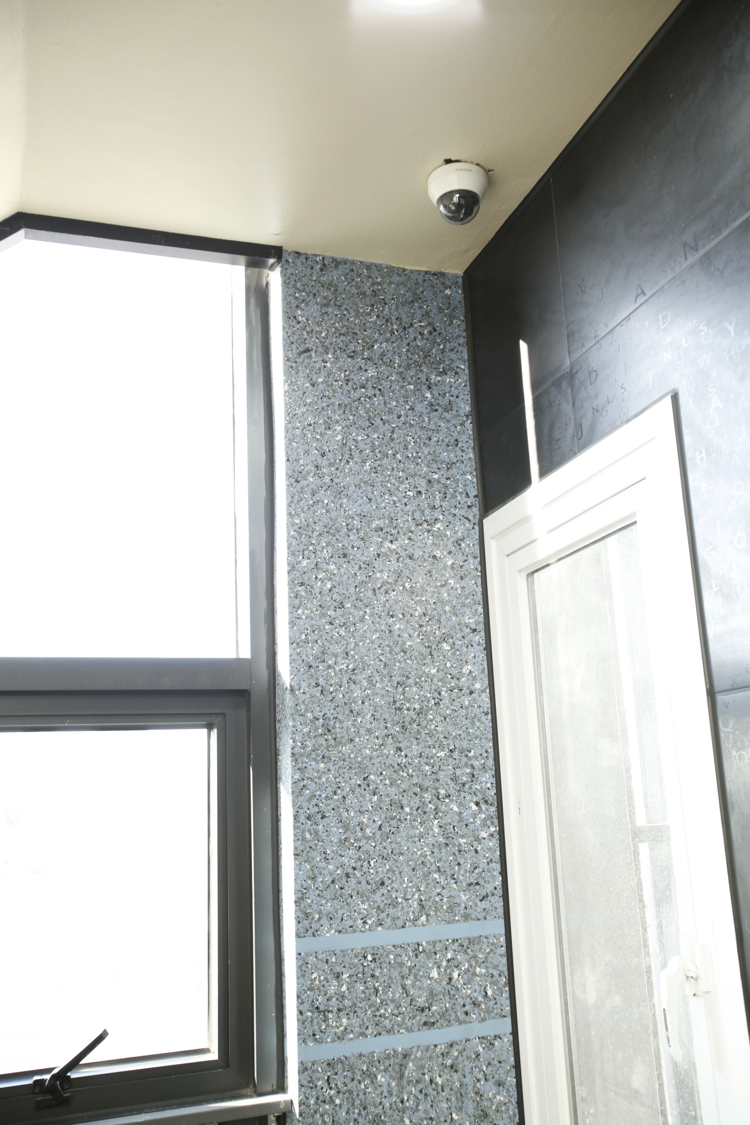 A room with a window, a door, and a textured wall.