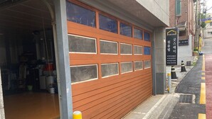 A garage door with a wooden finish and multiple rectangular windows. - The Core Albergue - Hostel (Seoul)