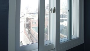 A window with white frames and a view of buildings outside. - The Core Albergue - Hostel (Seoul)