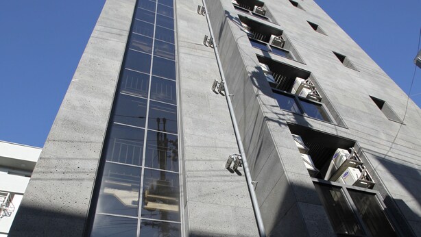 A tall building with a reflective glass facade and multiple balconies. - The Core Albergue - Hostel (Seoul)