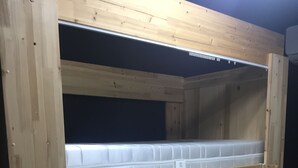 A bunk bed with a wooden frame and a mattress on the lower bunk. - The Core Albergue - Hostel (Seoul)