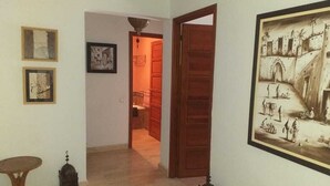 A hallway with a wooden door, a framed picture, and a small table.
