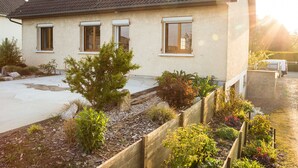 Ein Haus mit Ziegeldach, einem Vorgarten mit verschiedenen Pflanzen und einem gepflasterten Auffahrt.