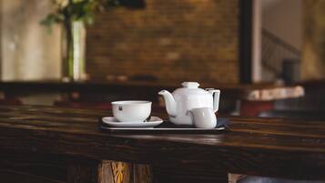 A wooden table with a teapot and cup, a vase with flowers, and hanging pendant lights.