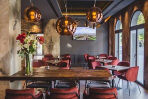 A restaurant with red chairs, a wooden table, and hanging spherical lights. - Boscovich Boutique Hotel (Podgorica)