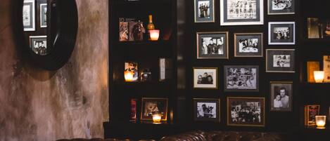 A dimly lit bar area with leather seating and framed photographs on the wall.