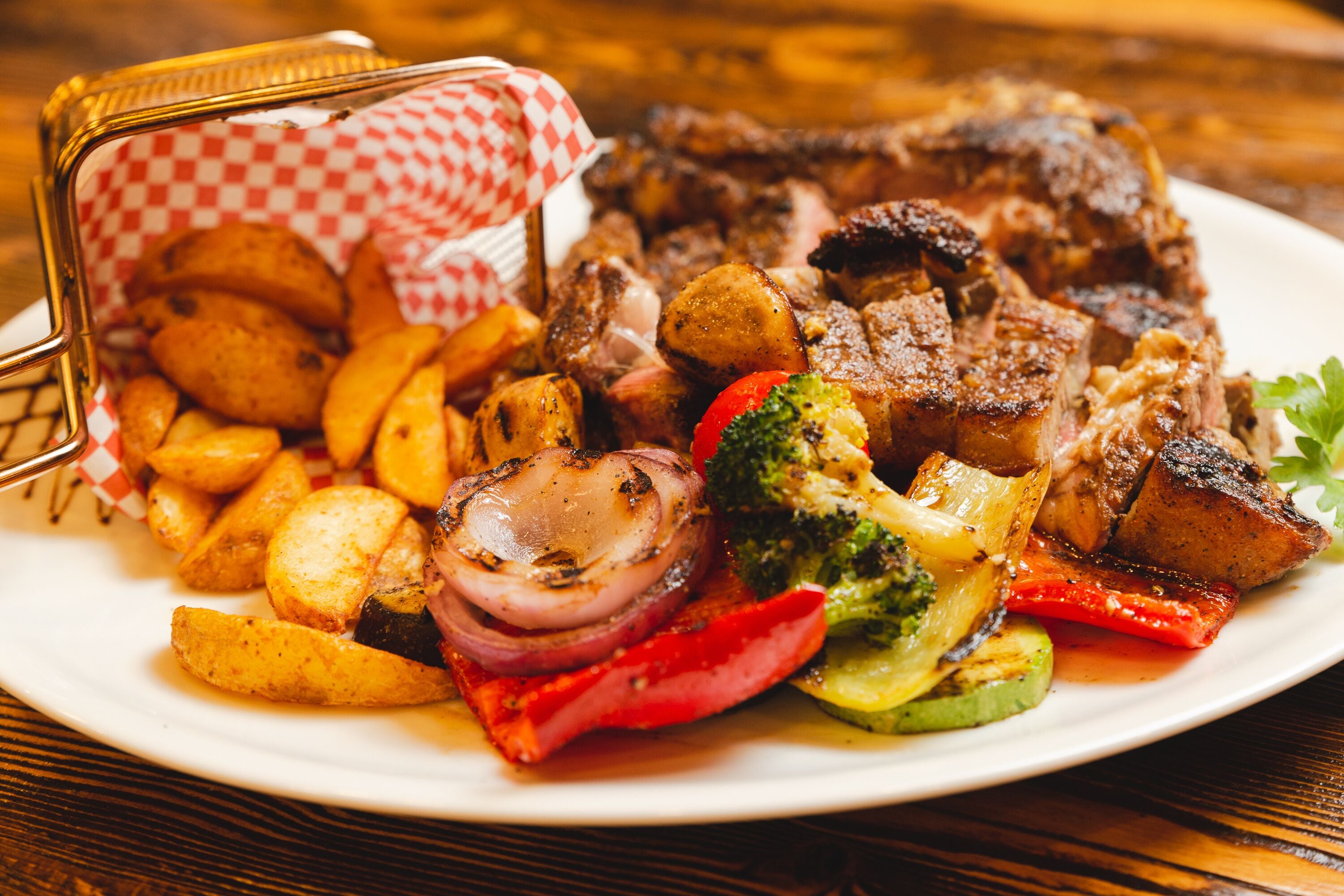 A plate of grilled steak with vegetables and potatoes.