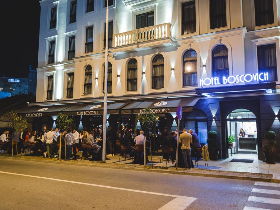 A hotel with a classic facade, outdoor seating area, and a visible entrance.