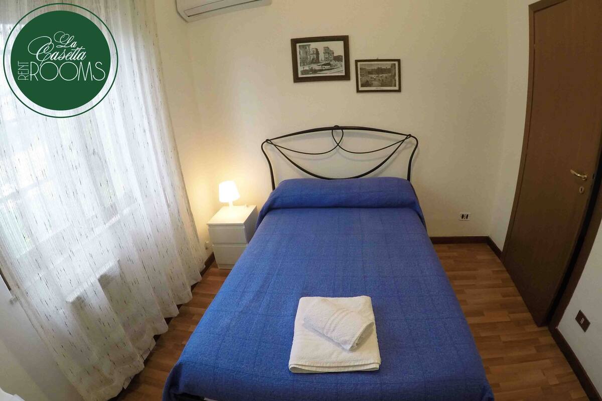 A bedroom with a bed, a nightstand, a lamp, and a door.