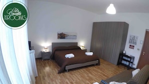 A bedroom with a bed, bedside tables, a wardrobe, a sofa, and a desk. - La Casetta (Palermo)