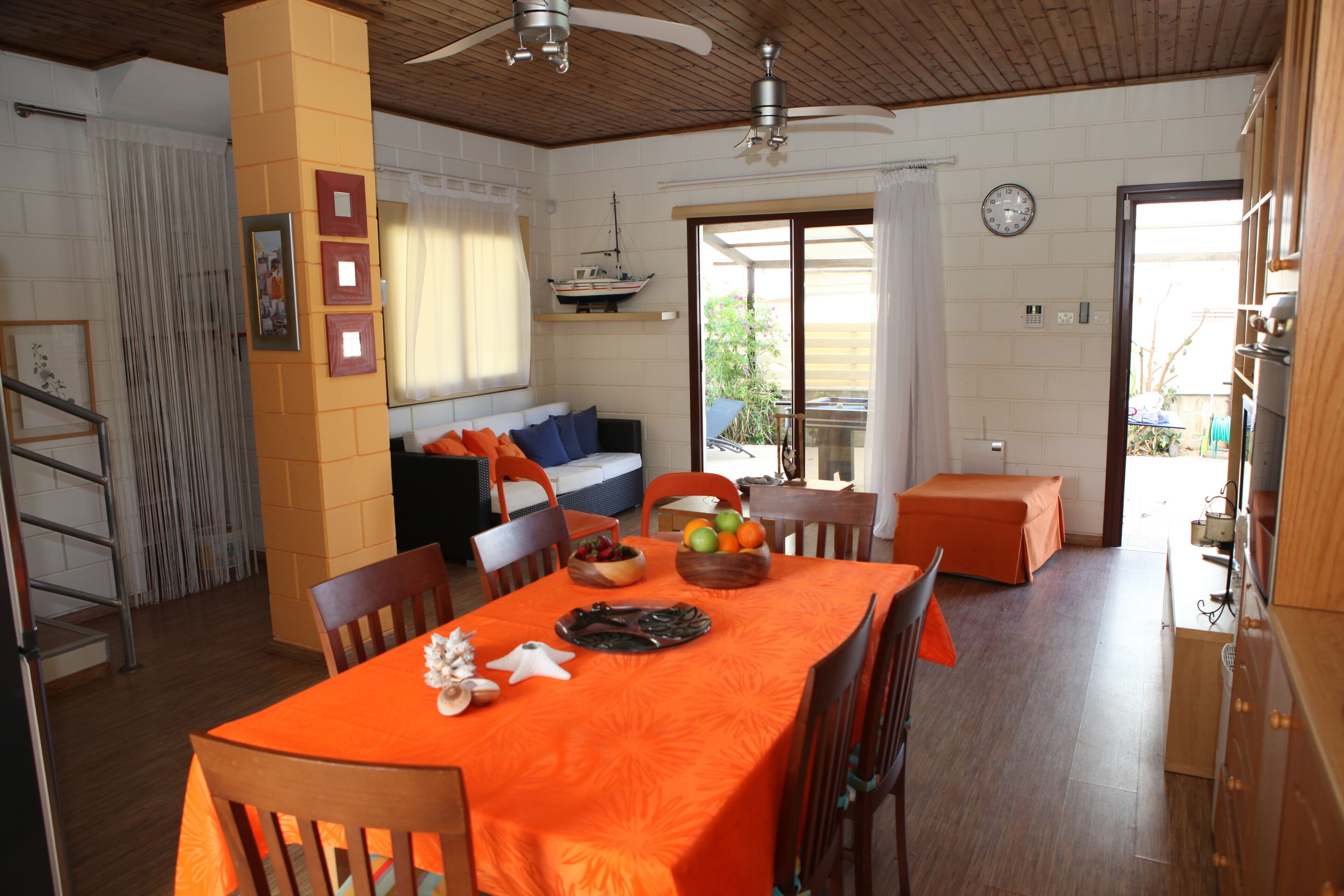 A dining area with a table set for four, a sofa, and a balcony with a view.
