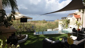 Eine Terrasse mit Gartenmöbeln, einem Pool und Blick auf den Ozean.