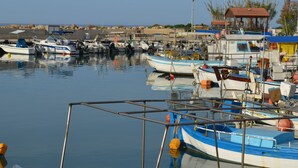 Ein Yachthafen mit mehreren festgemachten Booten, ein kleines Gebäude mit rotem Dach und ruhiges Wasser, das die Boote spiegelt.