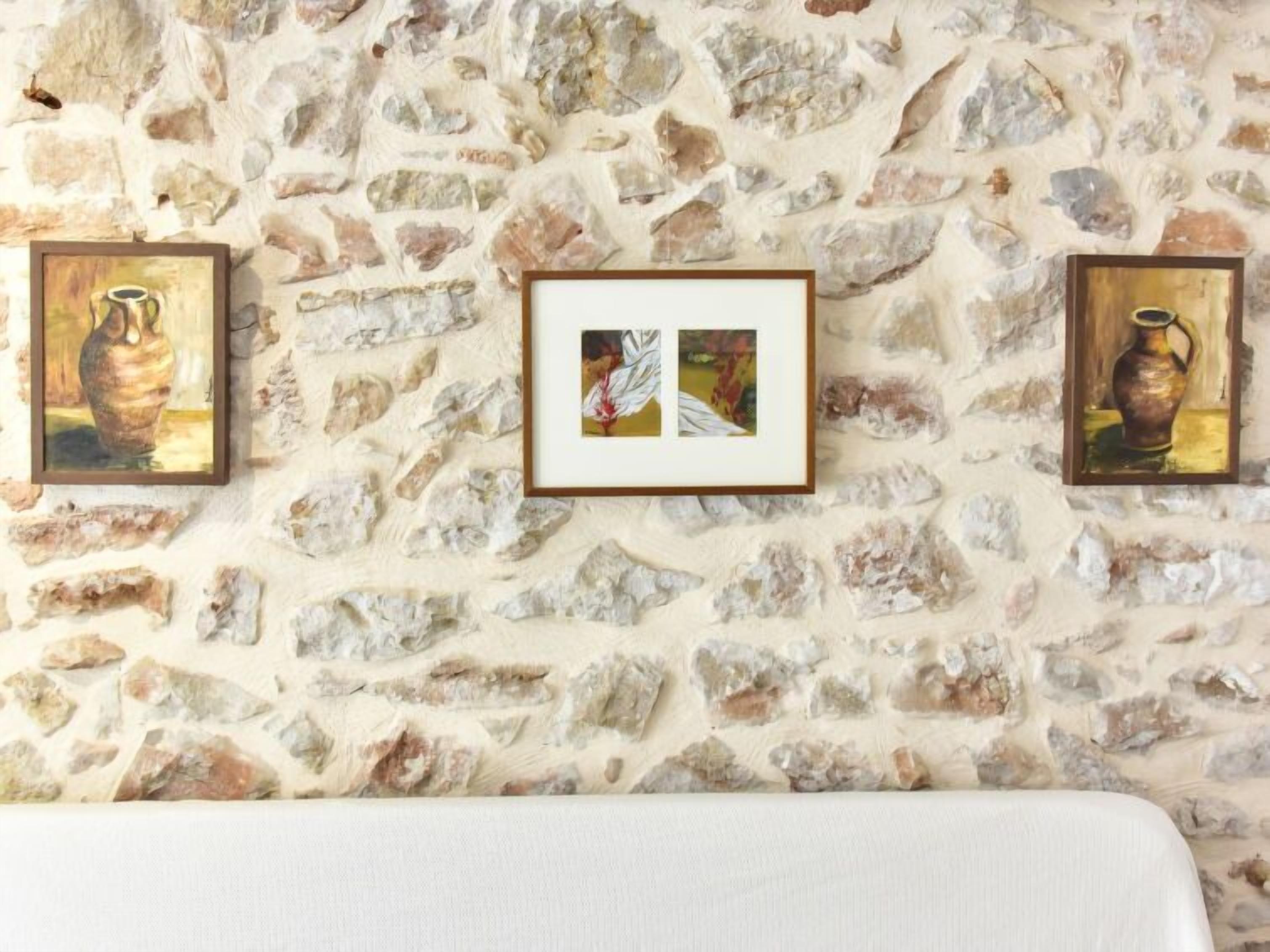 A stone wall with three framed artworks depicting vases.