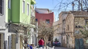 An outdoor cafe with white plastic chairs and tables, surrounded by buildings with various architectural styles. - Caseta Blanqueta by Interhome (Dénia)