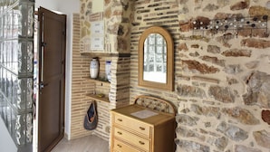 A room with a stone wall, wooden furniture, a mirror, and a hanging coat rack. - Caseta Blanqueta by Interhome (Dénia)