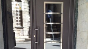 A modern building entrance with a dark brown door, a metal handle, and a glass panel. - Sunny & Happy Apartment Historic Center (Thessaloniki)