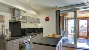 Een moderne keuken met roestvrijstalen apparatuur, een centraal eiland en een schuifdeur naar een buitenruimte.