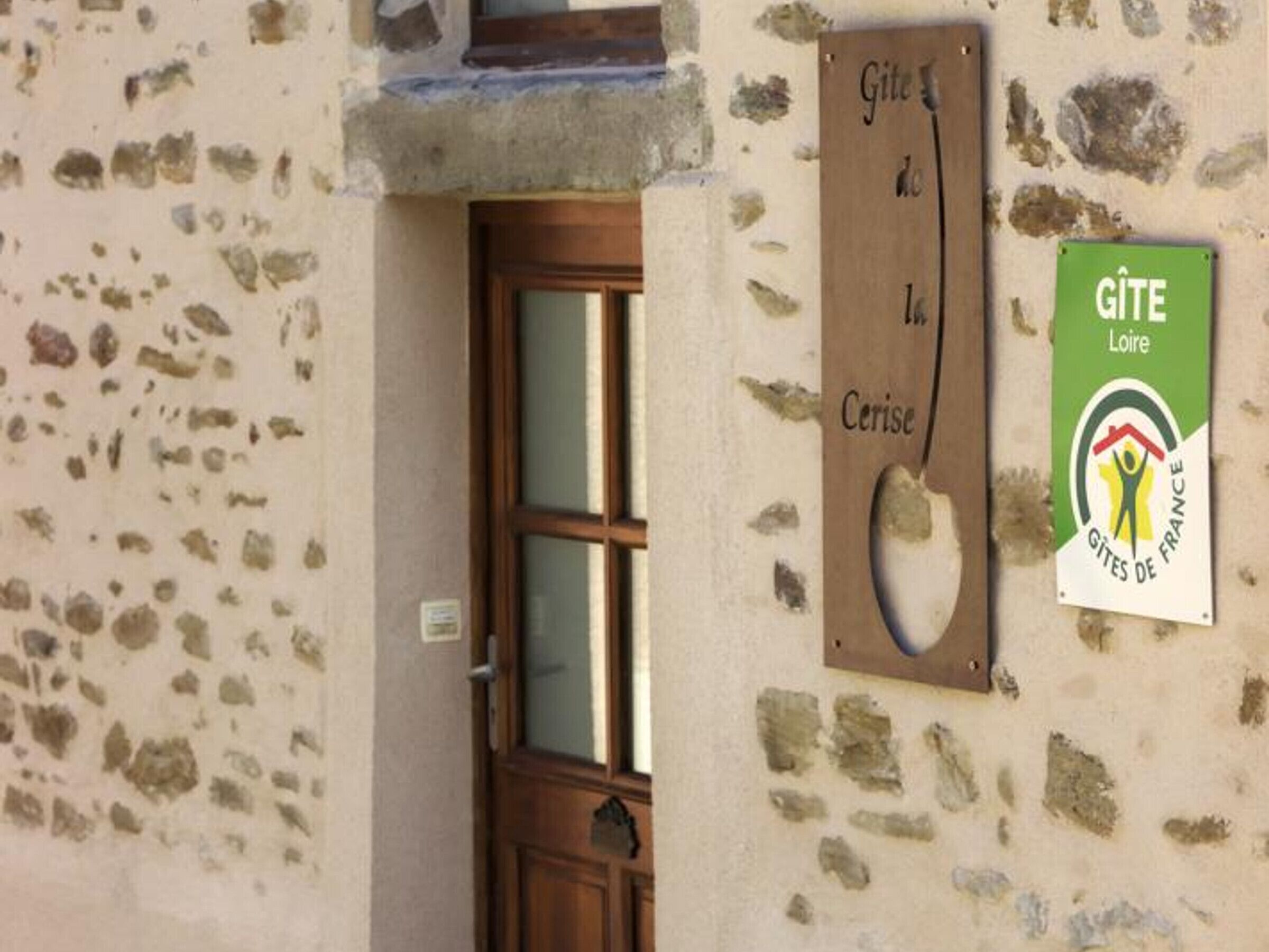 A stone building with a wooden door and a sign indicating 'Gîte de Cerise'.
