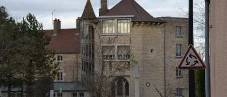 A historic building with a turret and arched windows, a roundabout, and a no-entry sign.