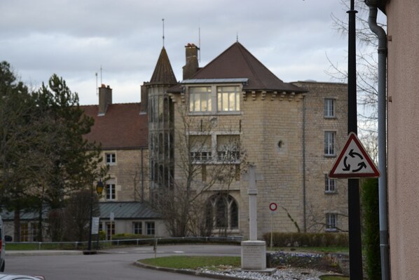 Un bâtiment historique doté d’une tourelle et de fenêtres en arc de cercle, un rond-point et un panneau indiquant l’interdiction d’accès.