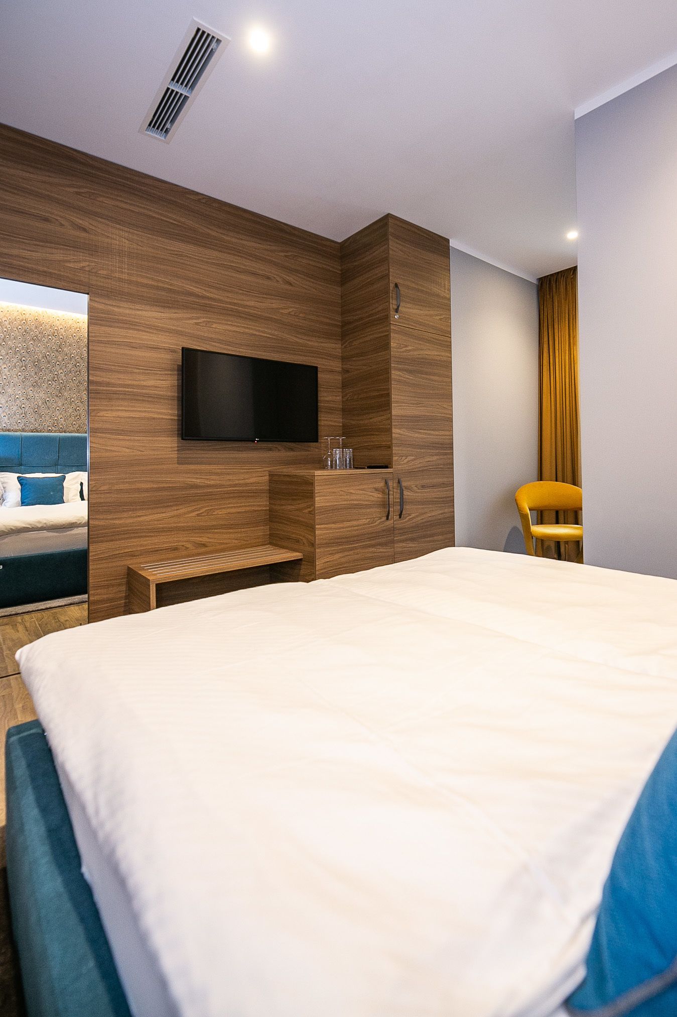 Un dormitorio moderno con una cama grande, un televisor de pantalla plana en la pared y un armario de madera.