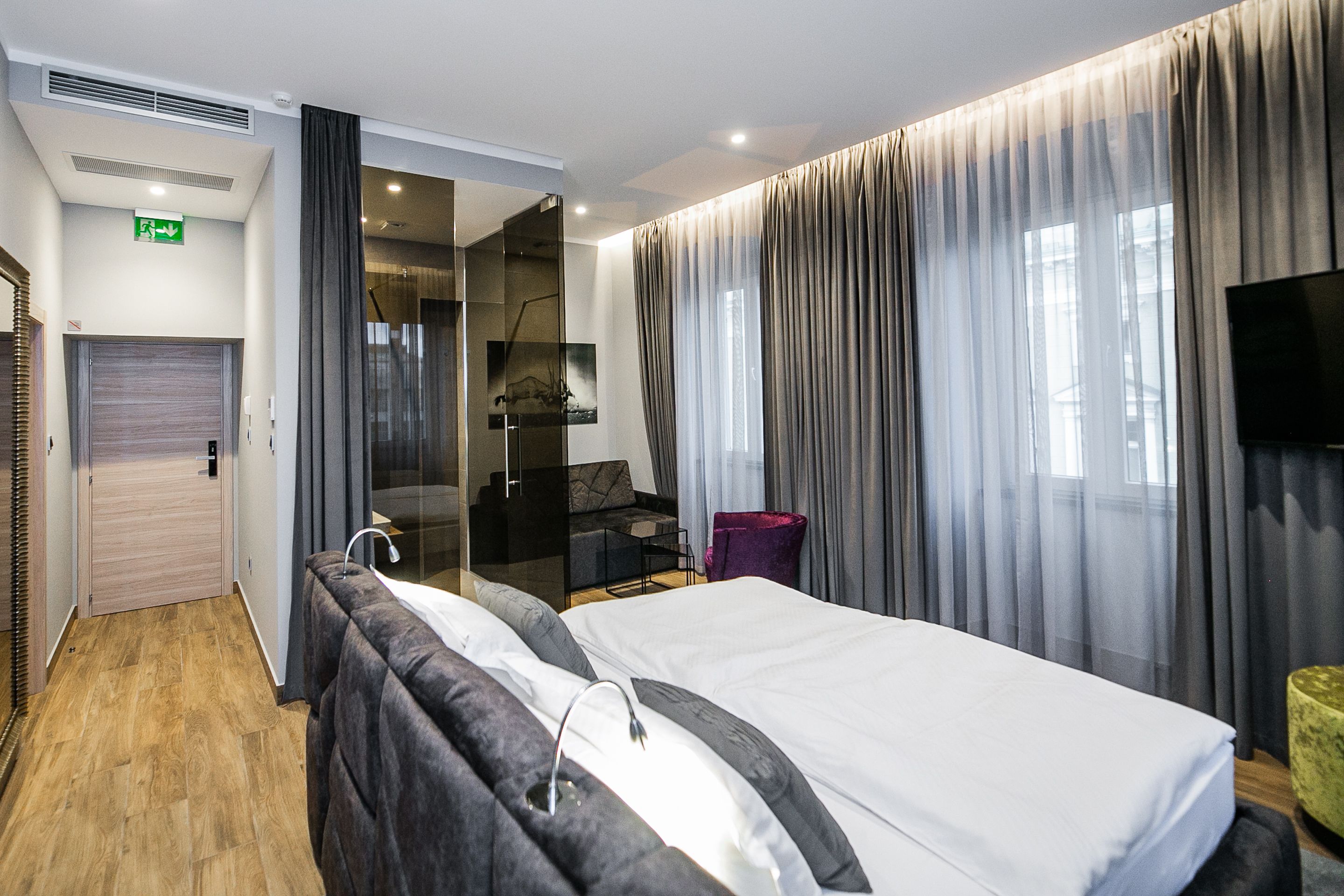 A modern hotel room with a large bed, a desk, a chair, and a television.