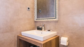 A modern bathroom with a wooden vanity, a large mirror, and a built-in shelf for towels.