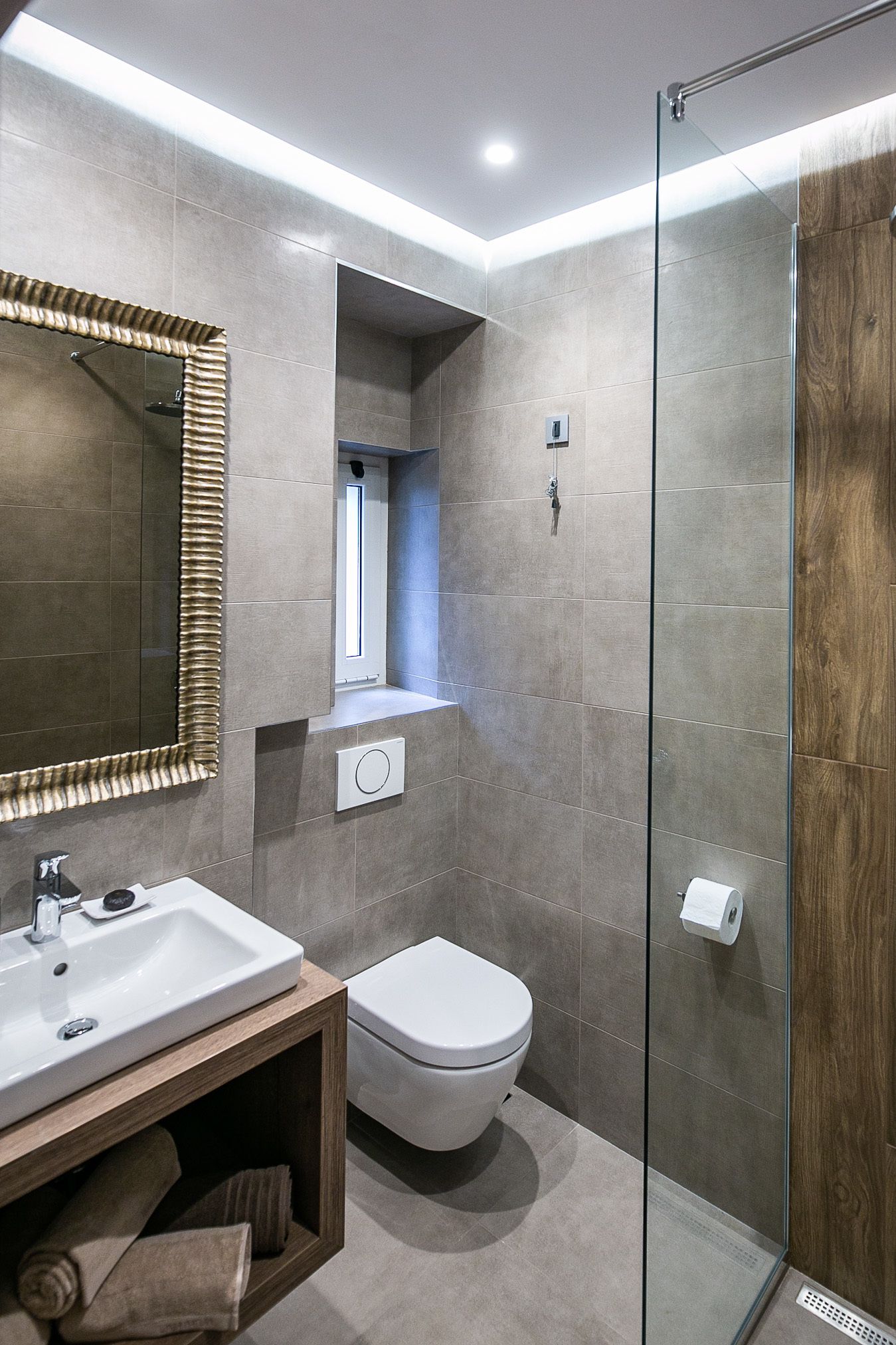 A modern bathroom with a glass shower enclosure, a wooden vanity, and a large mirror.