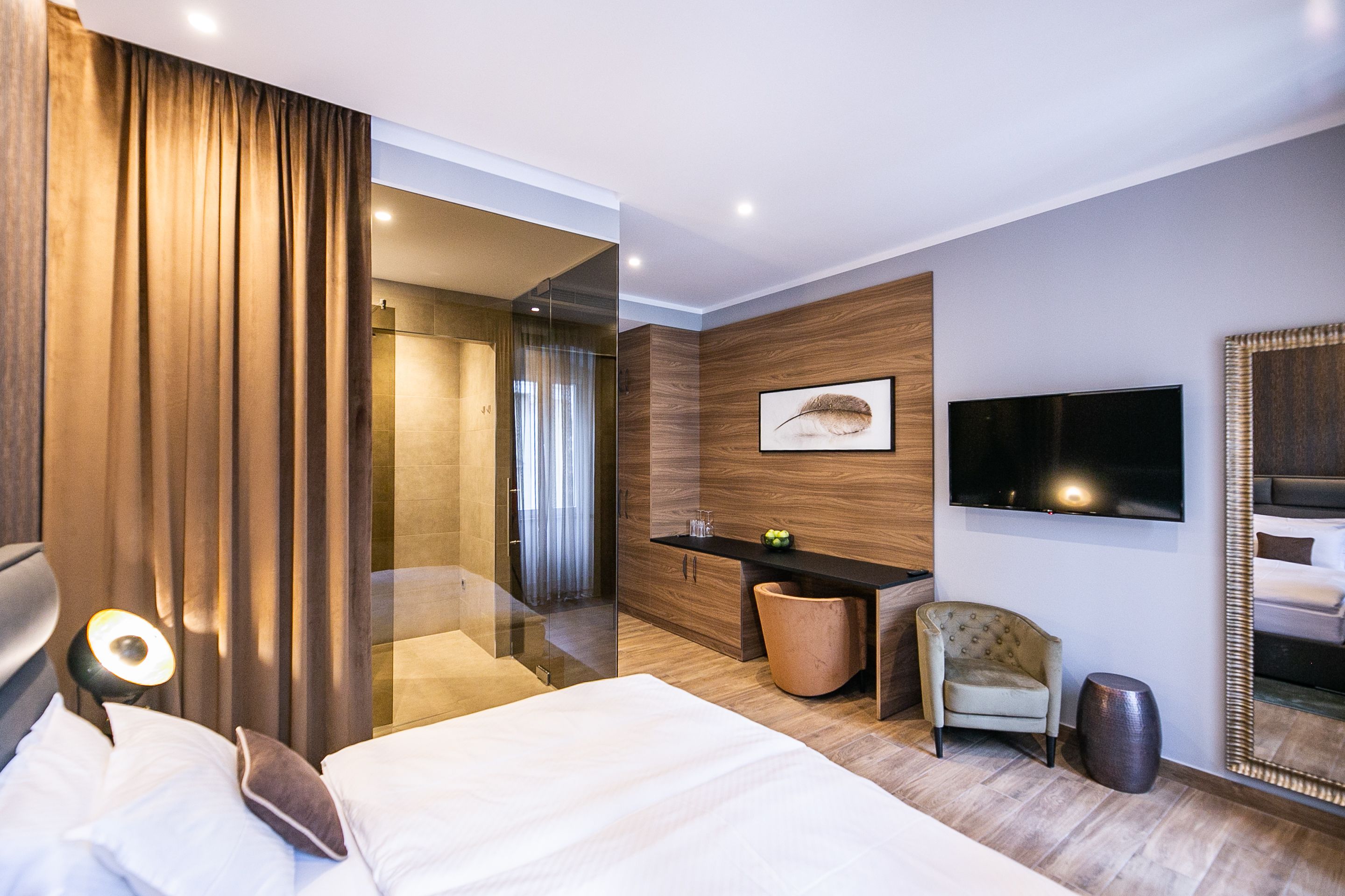Een moderne hotelkamer met een groot bed, een bureau met stoel, een televisie en een spiegel.