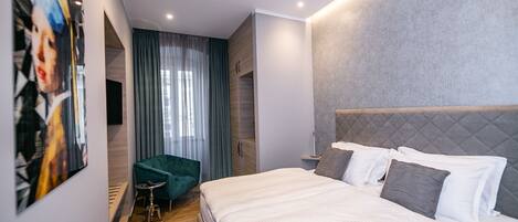Un dormitorio moderno con una cama grande, un sillón verde y un cuadro en la pared.