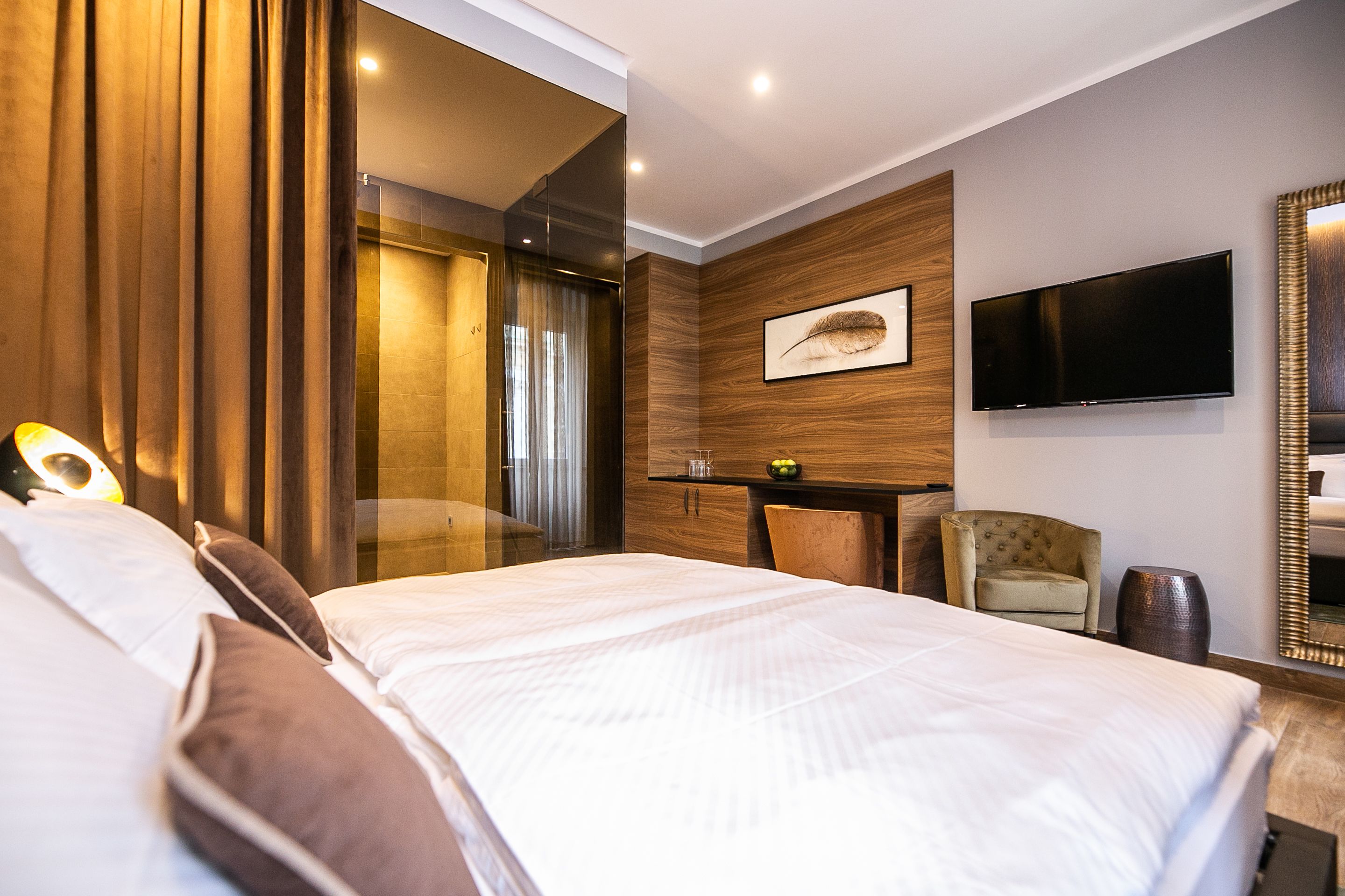 Une chambre d’hôtel moderne équipée d’un grand lit, d’un bureau, d’une chaise, d’un téléviseur à écran plat et d’un miroir.