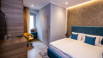 A modern bedroom with a large bed, a desk, a chair, and a wardrobe.