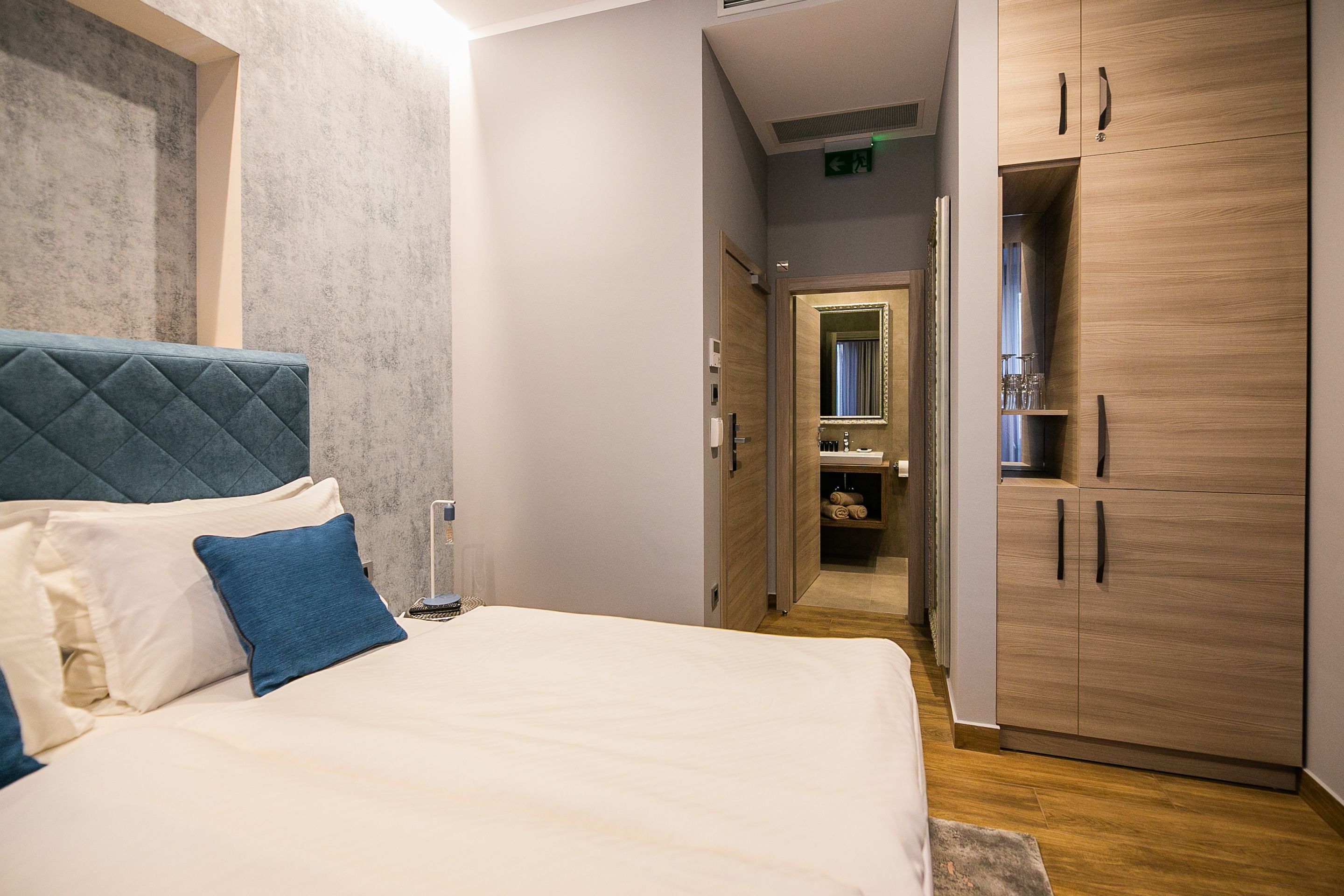 A bedroom with a bed, a wardrobe, and a bathroom visible through an open door.