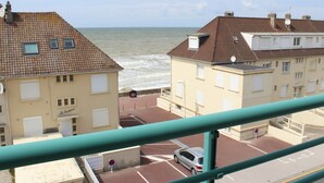 Un edificio frente al mar con techo de tejas, zona de estacionamiento y vistas al océano.