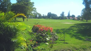 Een golfbaan met weelderig groen, een verzorgd gazon en diverse bomen.
